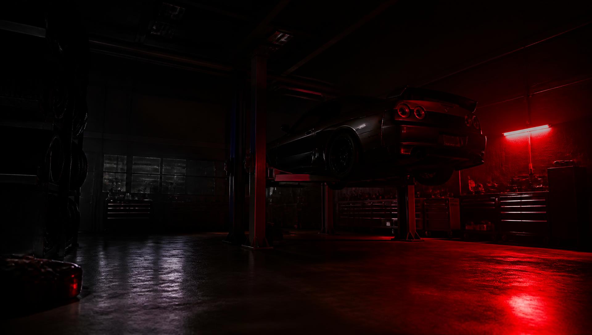 Dark auto repair garage with a car on a lift under red light